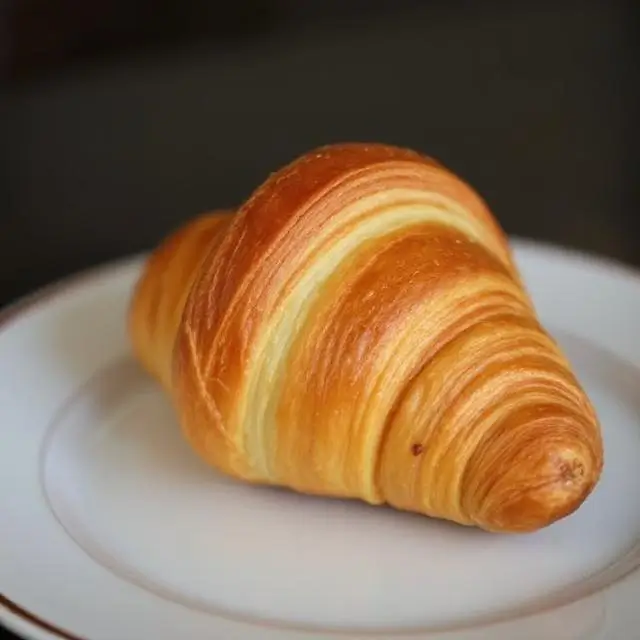 A flaky, golden-brown croissant on a plate.